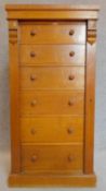 A Victorian honey oak Wellington chest of six oak lined graduating drawers flanked by carved