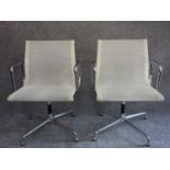 A pair of white mesh and chrome swivel armchairs designed by Charles Eames, Vitra makers label to