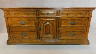 A French provincial style oak sideboard fitted with an arrangement of drawers and a central cupboard