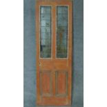 A 19th century pitch pine door with inset coloured leaded glass panels. H.196 W.66cm