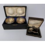A pair of raised pierced cups in leather case and cased childs spoon and pusher, cups by Deakin