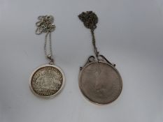 Two silver coins in silver and white metal mounts on silver chains, an American one dollar coin,