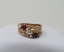 A Sapphire, Ruby and old mine diamond yellow metal jubilee ring, set to centre with a cushion shaped