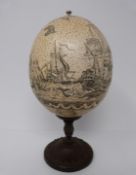 A scrimshaw ostrich egg on bronze stand, engraved with whales and sailing ship scene, map and