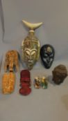 A collection of tribal masks and a buddha's head figure