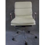 An Eames style swivel armchair in cream leather upholstery. H.96