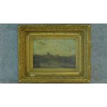 A 19th century gilt framed oil on canvas, A Norman church on the skyline in a village by an estuary,