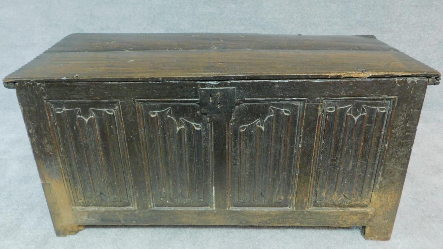 An early 17th century oak coffer with linenfold panels and hinged lidded top on block feet. H.62 W.