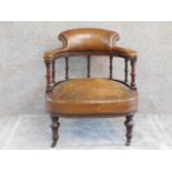 A late Victorian mahogany framed tub armchair in tan leather upholstery on ring turned supports