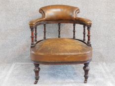 A late Victorian mahogany framed tub armchair in tan leather upholstery on ring turned supports