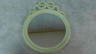 A circular painted wall mirror with ribbon cresting. 75x61cm