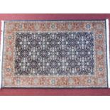 A Persian rug with repeating petal motifs on a sapphire field surrounded by a rouged floral border
