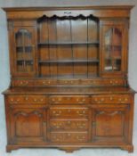 A Georgian style oak dresser the upper glazed and shelved section above base fitted with cupboards