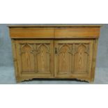 A 19th century pitch pine ecclesiastical style two door sidebaord. H.98 W.143 D.53cm