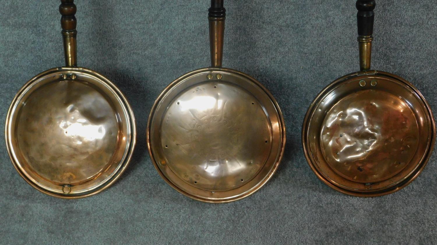 A collection of three 19th century copper warming pans with turned handles. W.116cm. - Image 2 of 6