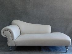 A Victorian style chaise longue on silvered turned supports. H.90 W.188 D.93cm (one caster snapped).