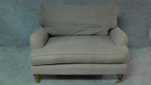 A contemporary Howard style small sofa on turned tapering supports terminating in brass cup casters.