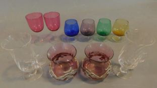 A collection of coloured glass to include a pair of cranberry glass jars with applied sycamore