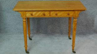 A Victorian satin birch writing table by Holland and Son with two frieze drawers on turned