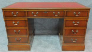 A Georgian style mahogany pedestal desk with red tooled leather inset top and arrangement of nine