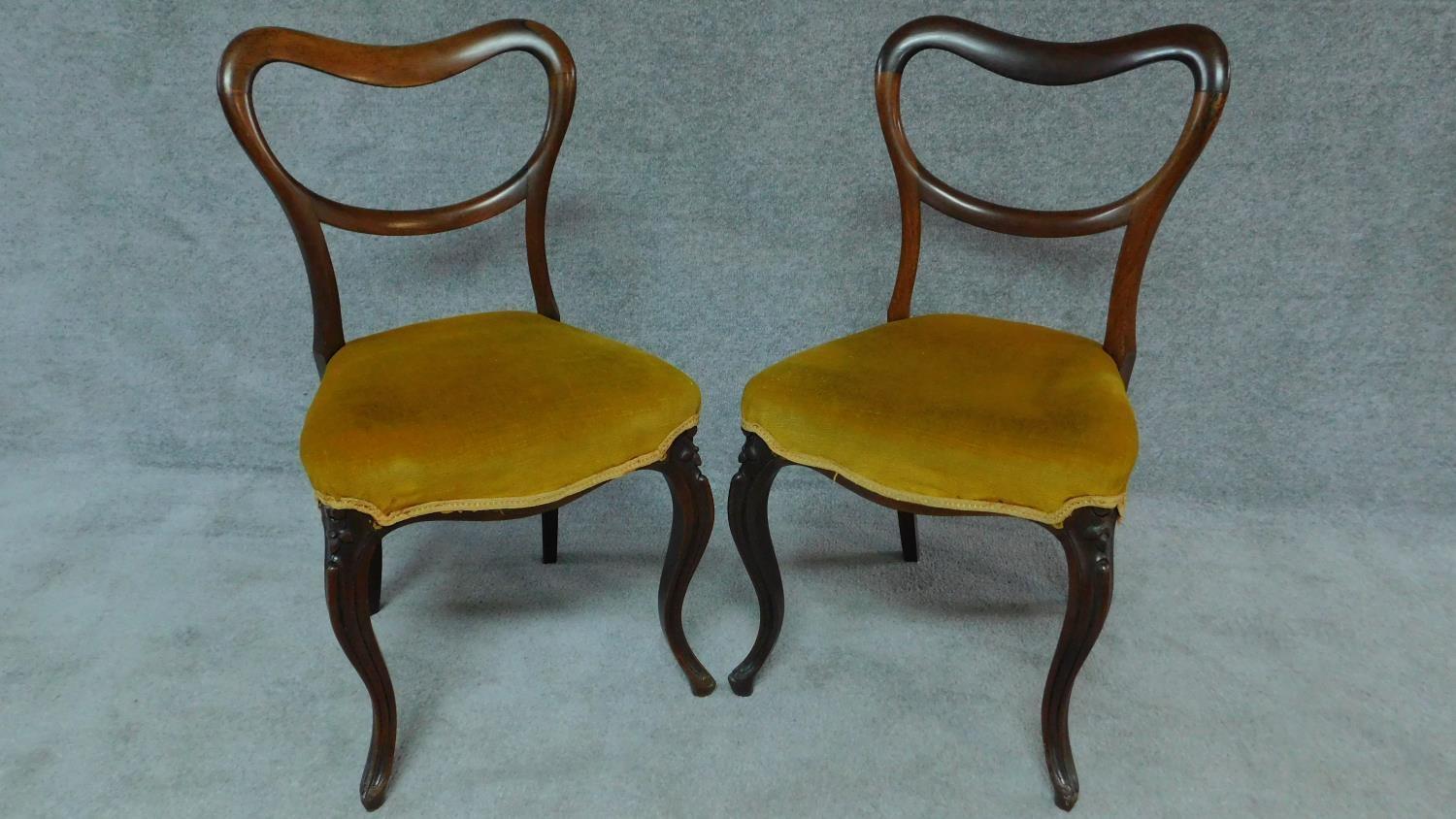 A pair of Victorian rosewood dining chairs with kidney shaped backs on cabriole supports. H.82cm