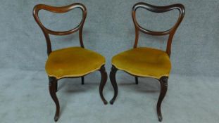 A pair of Victorian rosewood dining chairs with kidney shaped backs on cabriole supports. H.82cm