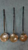 A collection of three 19th century copper warming pans with turned handles. W.116cm.