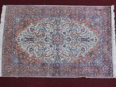 A Persian hand woven Mahal style rug with central medallion on an ivory and terracotta field with