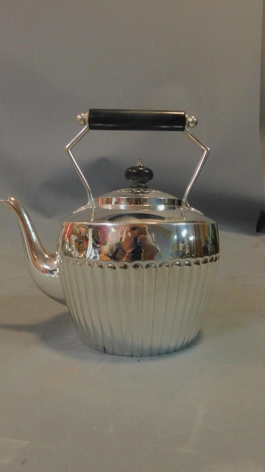 A collection of silver plated tea pots and jugs and a brass kettle, some with ebony handles.