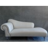 A Victorian style chaise longue on silvered turned supports. H.90 W.188 D.93cm (one caster snapped).