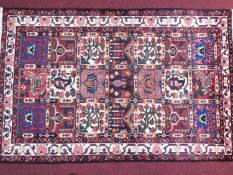 A North West Persian Bakhtiari rug, repeating floral panel motifs within stylised ivory floral