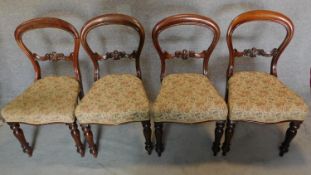 A set of four Victorian mahogany balloon backed dining chairs with floral tapestry style stuffover