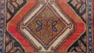 A Kurdish runner, central diamond medallions on rouge ground within multi-borders. L. 272cm W. 77cm