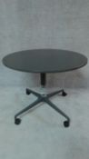 A dark grey Herman Miller table with circular top on quatreform base with casters. H.74 W.91 D.91cm