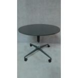 A dark grey Herman Miller table with circular top on quatreform base with casters. H.74 W.91 D.91cm