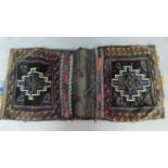 A pair of embroidered kelim saddlebags with abstract geometric design and a similar squab cushion.