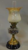 A late Victorian oil lamp with brass base on ebonised socle. H.57cm
