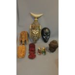 A collection of tribal masks and a buddha's head figure