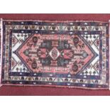 A Persian Shiraz style rug, central pendant on a rouge and cream ground, within floral border and