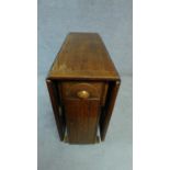 A mid 20th century oak drop flap dining table fitted frieze drawer and cupboard to the centre