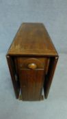 A mid 20th century oak drop flap dining table fitted frieze drawer and cupboard to the centre