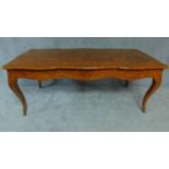 A Louis XV style kingwood library table with shaped and foliate inlaid top on cabriole supports L.