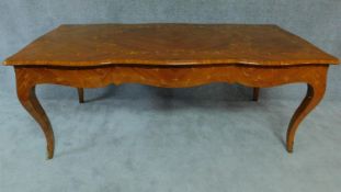 A Louis XV style kingwood library table with shaped and foliate inlaid top on cabriole supports L.