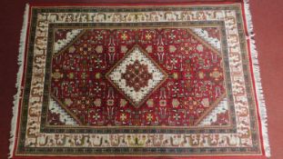 A Heriz style rug with central ivory pendant medallion on a rouge field set within floral and