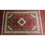 A Heriz style rug with central ivory pendant medallion on a rouge field set within floral and