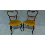 A pair of Victorian rosewood dining chairs with kidney shaped backs on cabriole supports. H.82cm