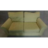 A two seater sofa in cream upholstery. 70x175x90cm