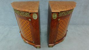 A pair of Empire style corner cabinets with marble tops, ormolu mounts and satinwood marquetry bowed