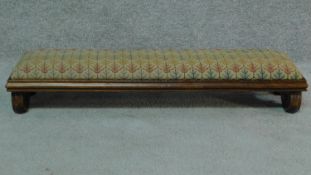 A William lV oak long footstool in original tapestry upholstery on scroll end supports. H.16 W.86