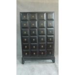 A large Chinese lacquered specimen style chest fitted with twenty four drawers with brass ring